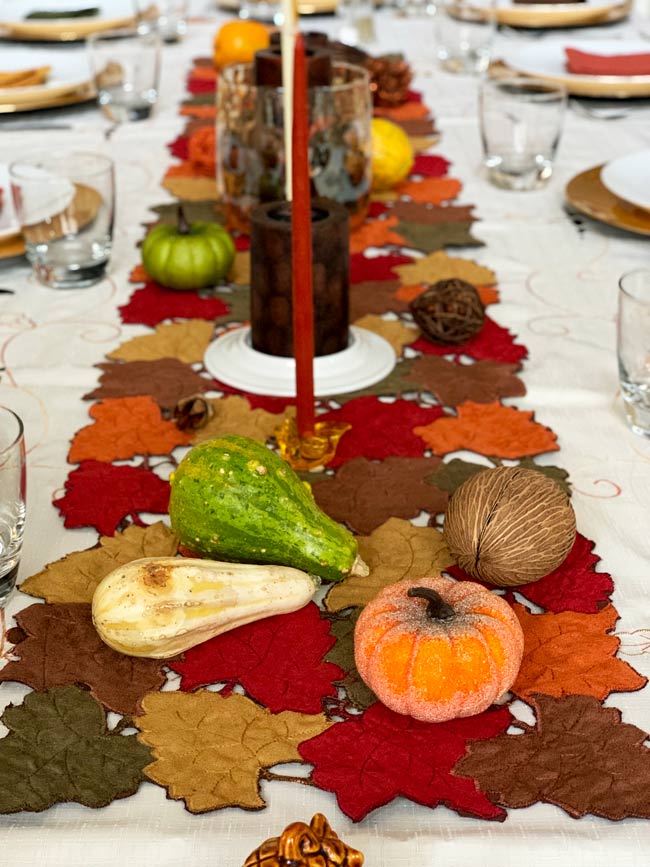 Thanksgiving table set with candles and gourds.