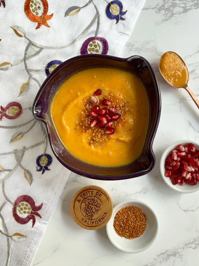 Squash soup with dukkah and pomegranate arils and copper spoon.