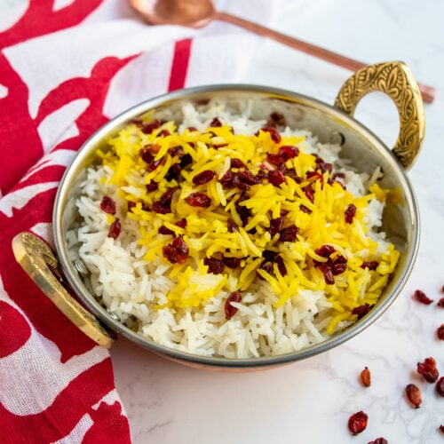 Instant Pot barberry rice in a copper bowl on a pomegranate scarf with a copper spoon in the background.
