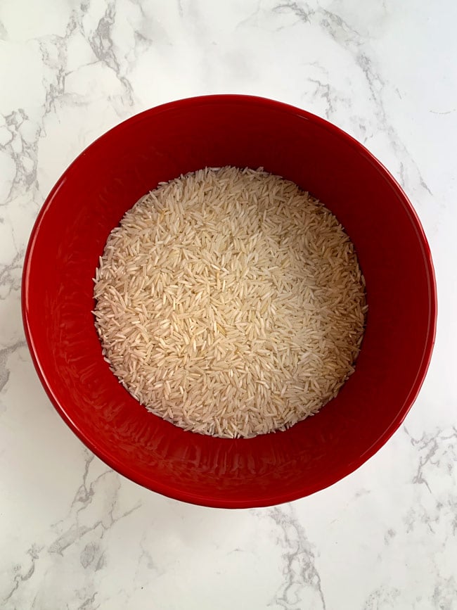 Dry basmati rice in red bowl.