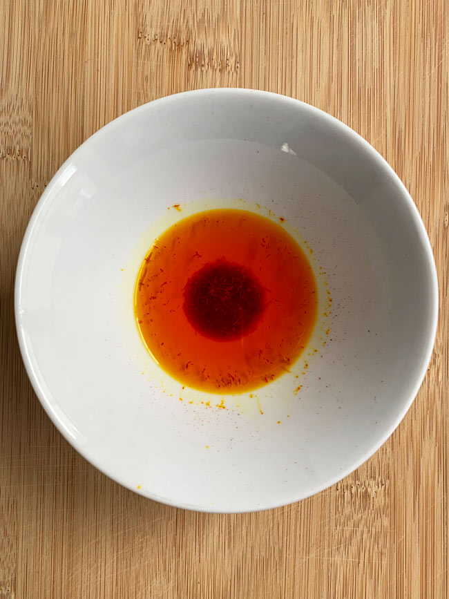 Saffron soaking in water in white bowl.