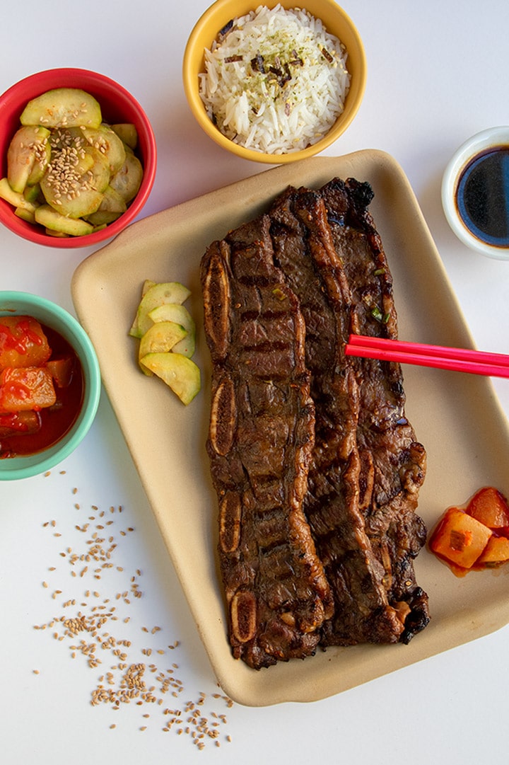 3 kalbi ribs with bowls of banchan (side dishes) ready for serving.