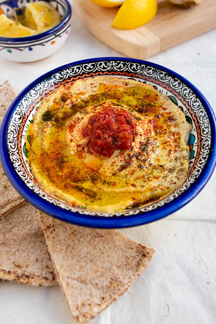 Angle shot of blue bowl filled with preserved lemon hummus
