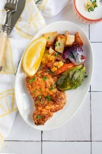 chicken and vegetables on white plate with lemon napkin