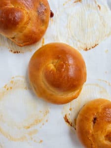 3 challah rolls at an angle on baked parchment paper