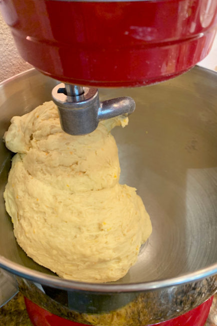 Challah dough in mixer being kneaded by dough hook.