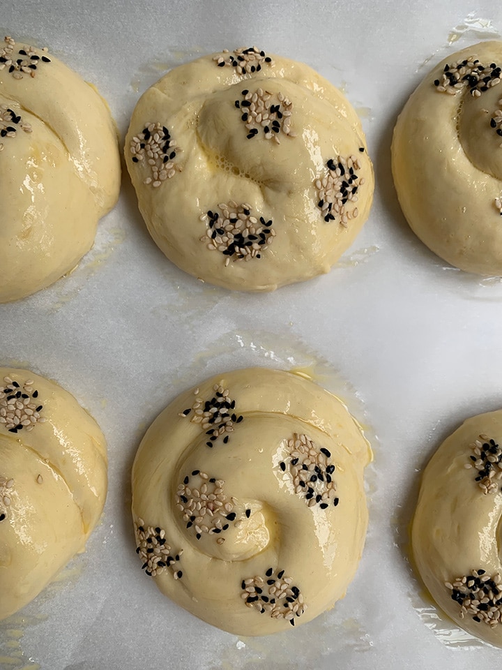 Egg washed challah rolls with dots of seeds applied, ready for the oven.