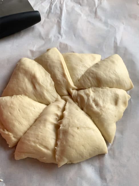 Challah dough divided into 8 triangular pieces.