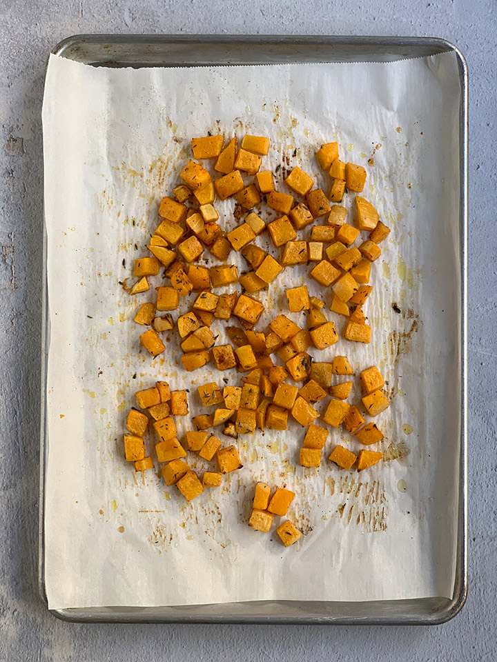 butternut squash cubes cooked on parchment-lined tray