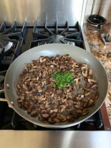 mushrooms cooked with parsley ready to be mixed in in the skillet