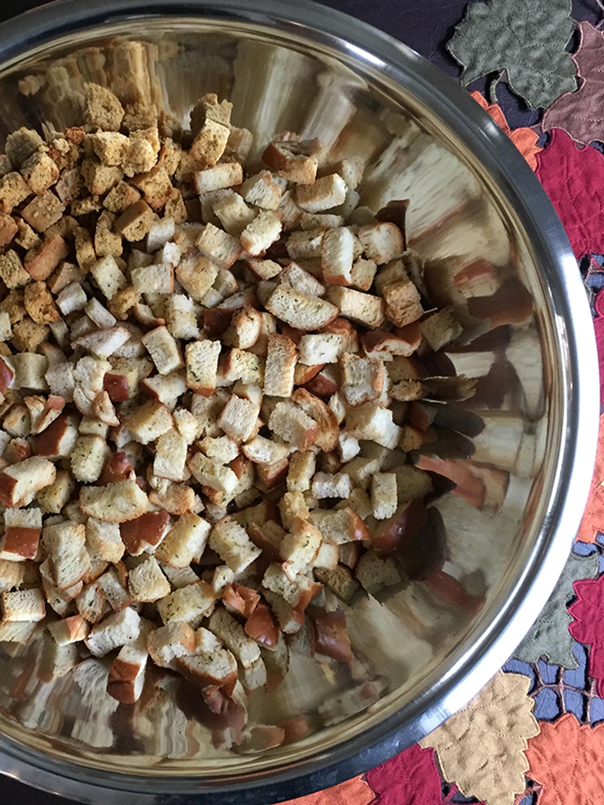 Stuffing bread cubes in large stainless steel bowl.