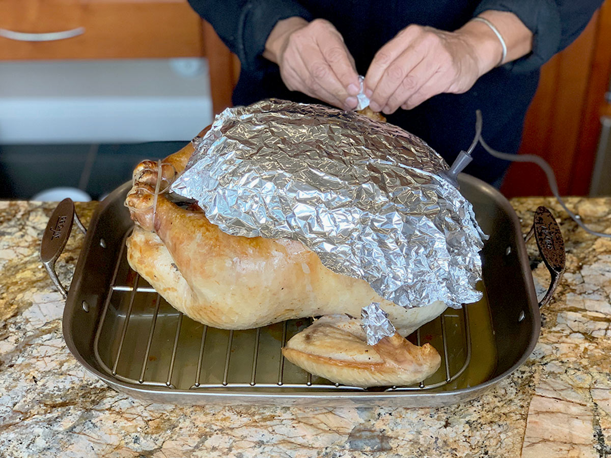 Foil cover on partially cooked turkey to protect the breast section from burning.