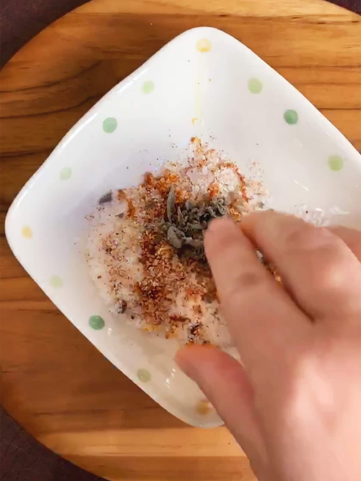 Hand mixing dry brine ingredients - salt, paprika, orange zest and dried sage.