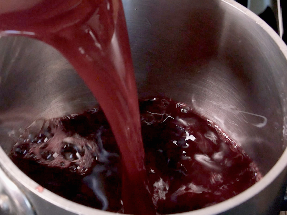 Pouring fresh red pomegranate juice into a sauce pan.