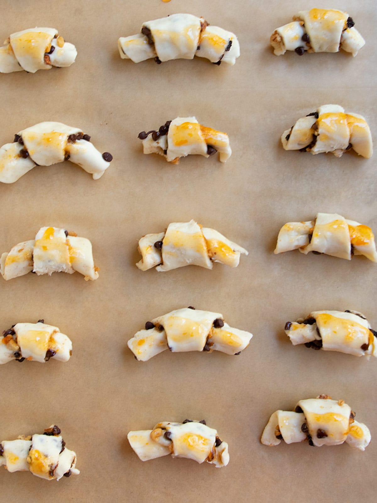 A tray of unbaked rugelach on brown parchment paper.