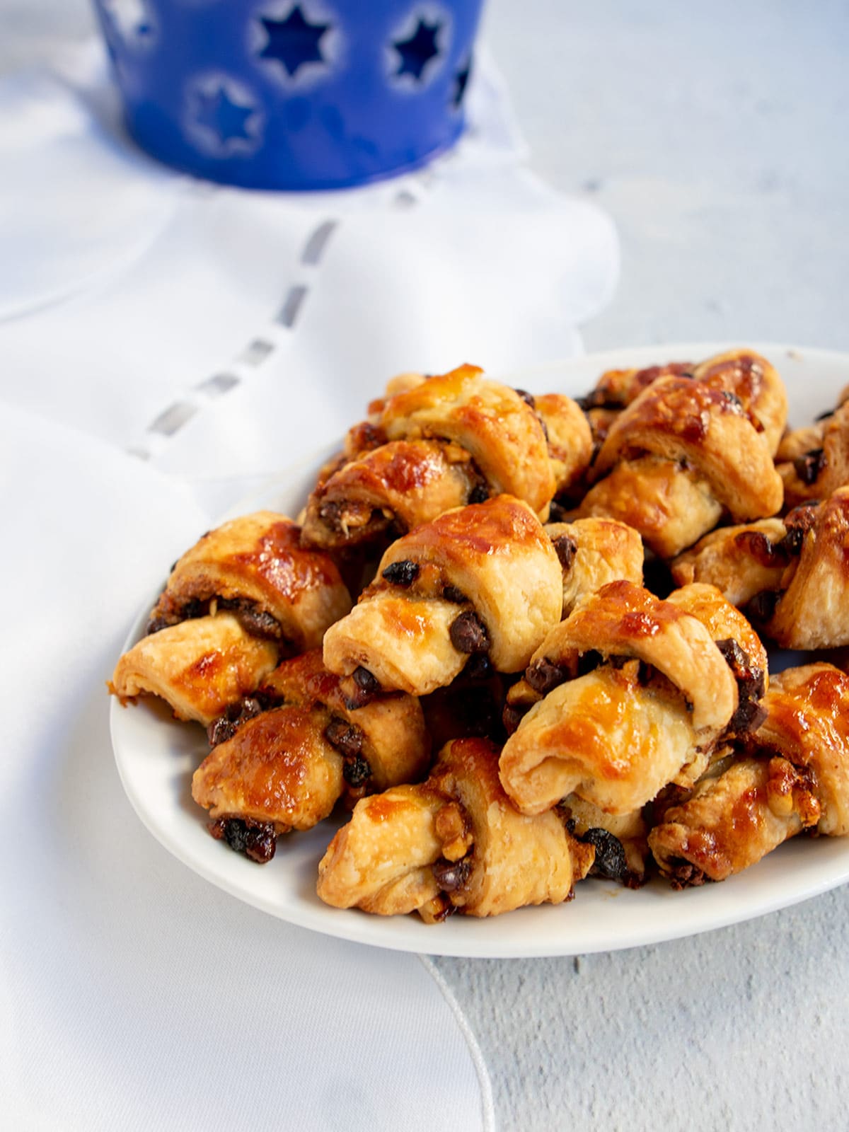 A plate of rugelach with Hanukkah decorations in the background.
