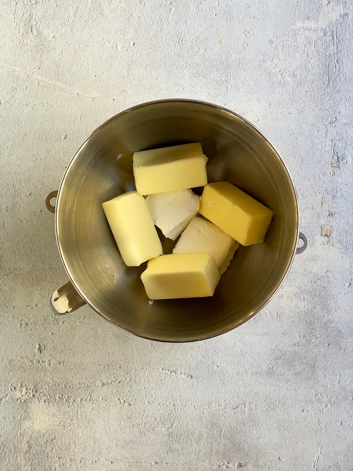 A metal mixing bowl of butter and cream cheese ready for mixing.