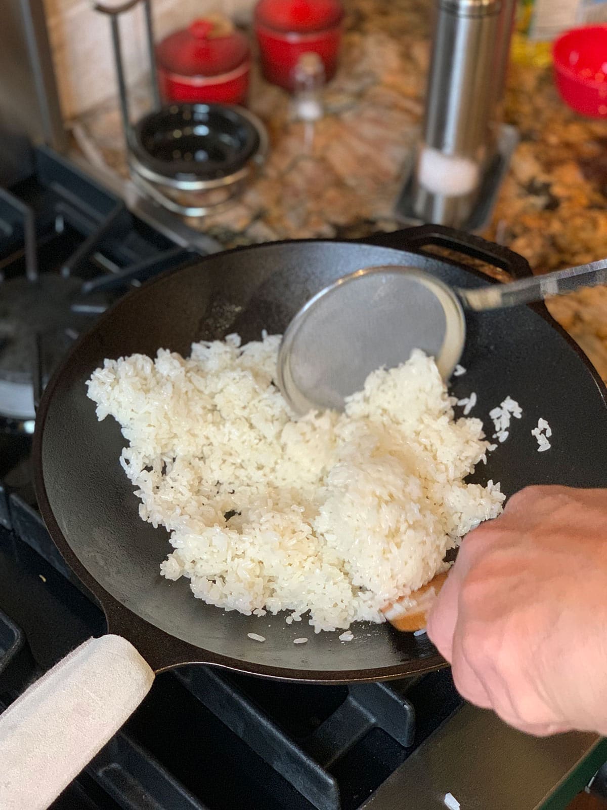 Mixing cooked rice with oil in hot wok for the fried rice recipe.
