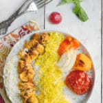 Chicken kabob with saffron rice and tomatoes on a white plate.