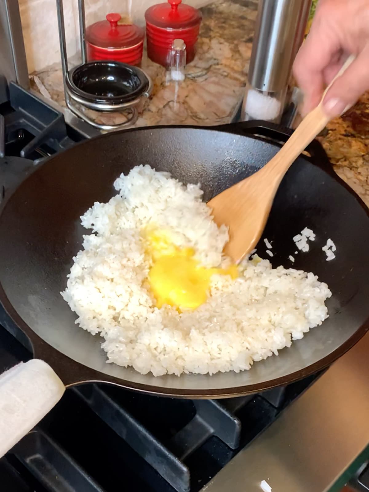 Adding egg into wok to mix with rice .