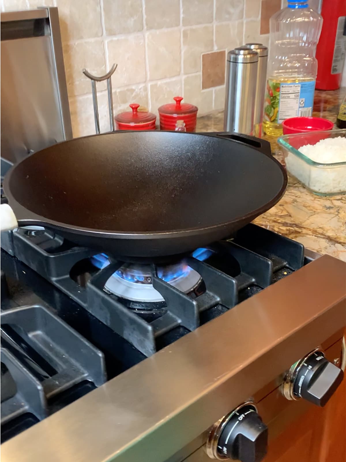 A cast iron wok heating up on stove top for leftover prime rib fried rice.