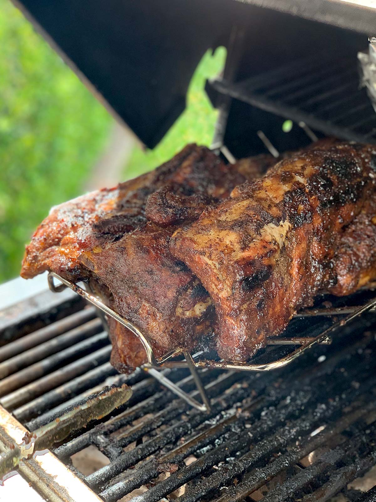 Ribs cooking on a rack on a gas grill.