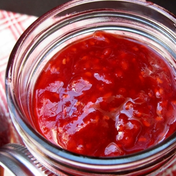8 ounce jar of raspberry apricot jam with the lid off.
