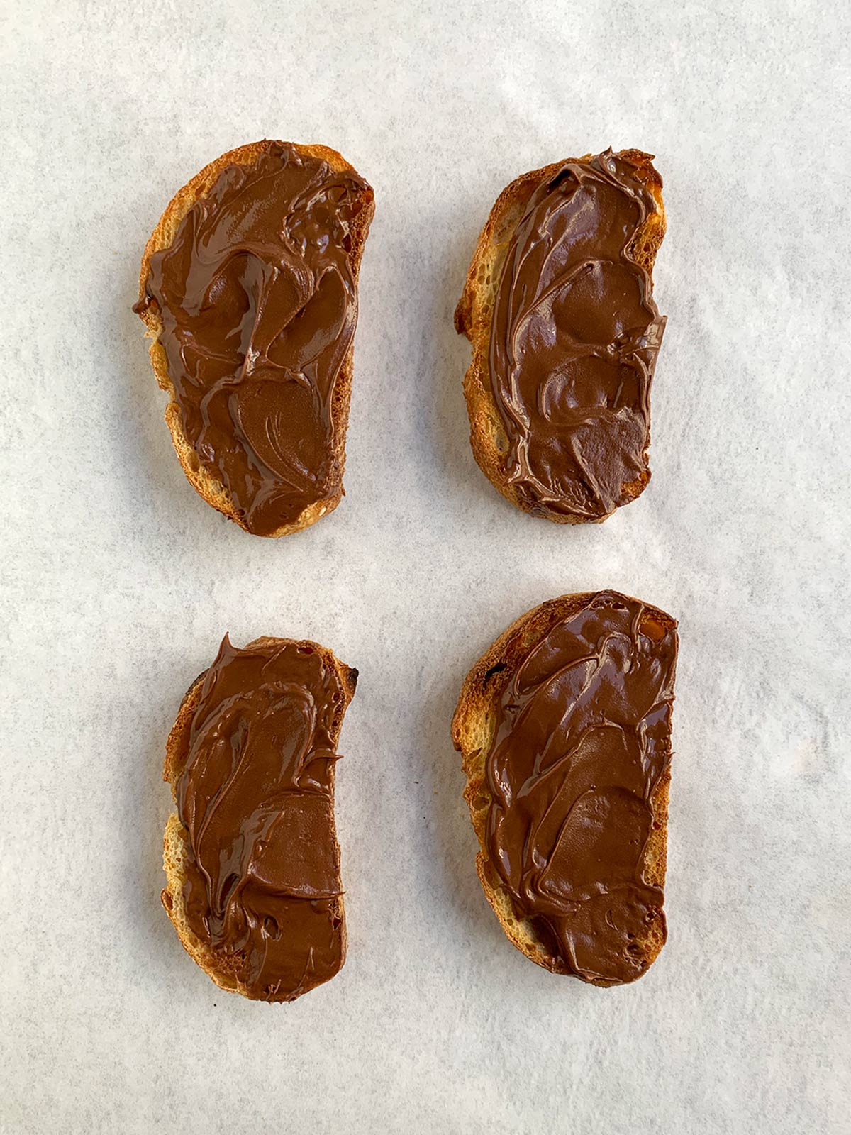 4 slices of mini toasts with nutella spread on top.
