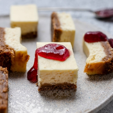 Lemon Cheesecake Bars on a gray plate with jam dripping off of a slice.