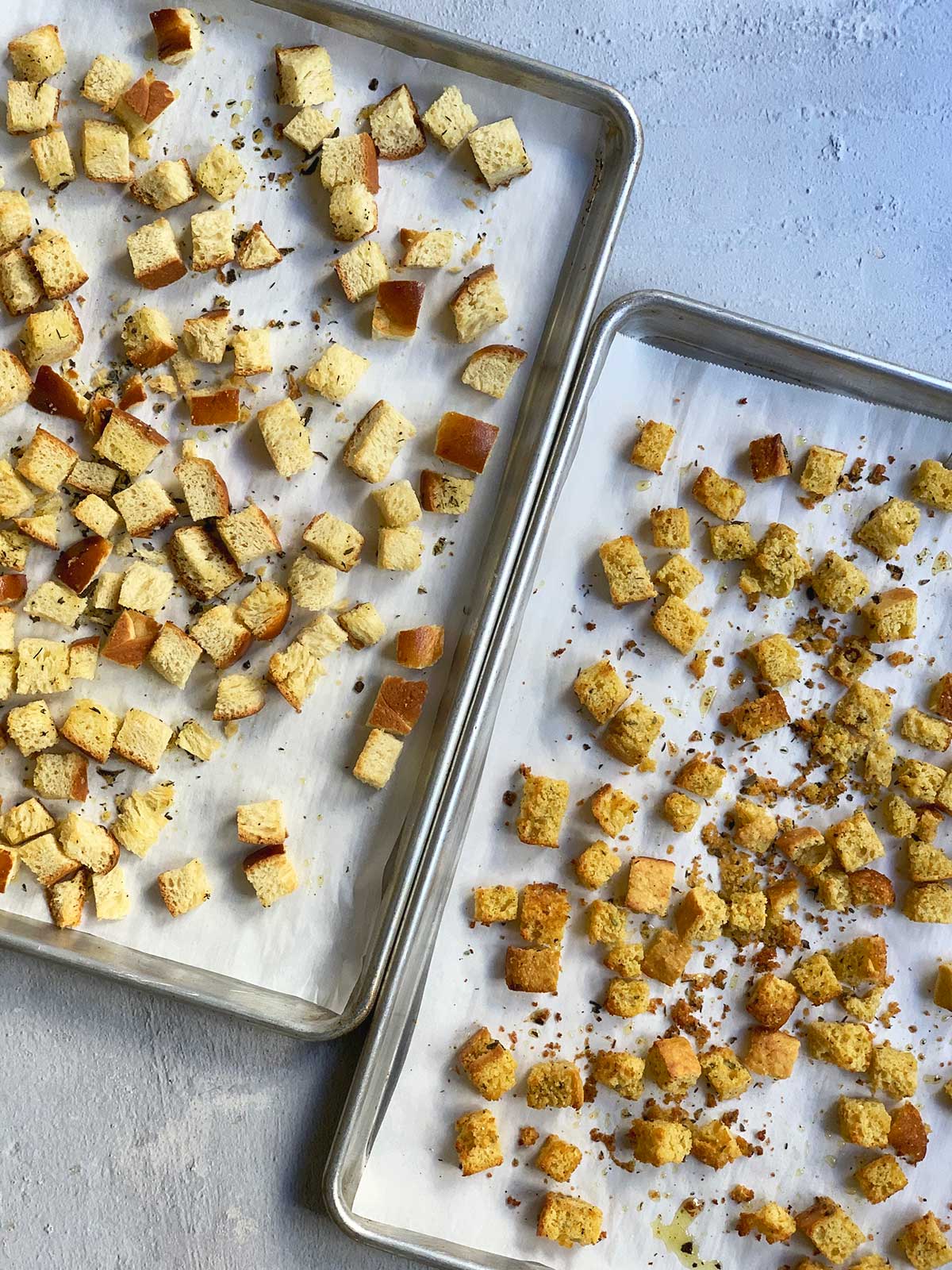 Two trays of baked stuffing cubes - cornbread and challah - shown at an angle.