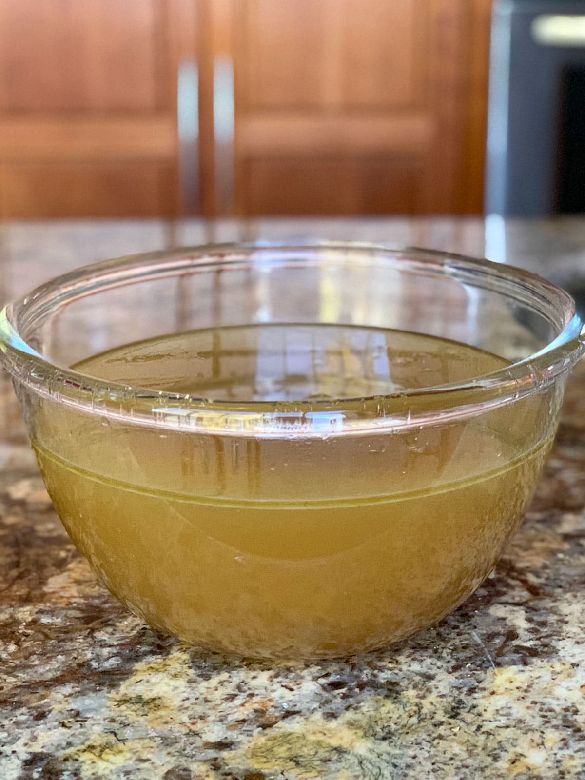 Roasted turkey stock in a glass bowl on a kitchen counter after being well strained.