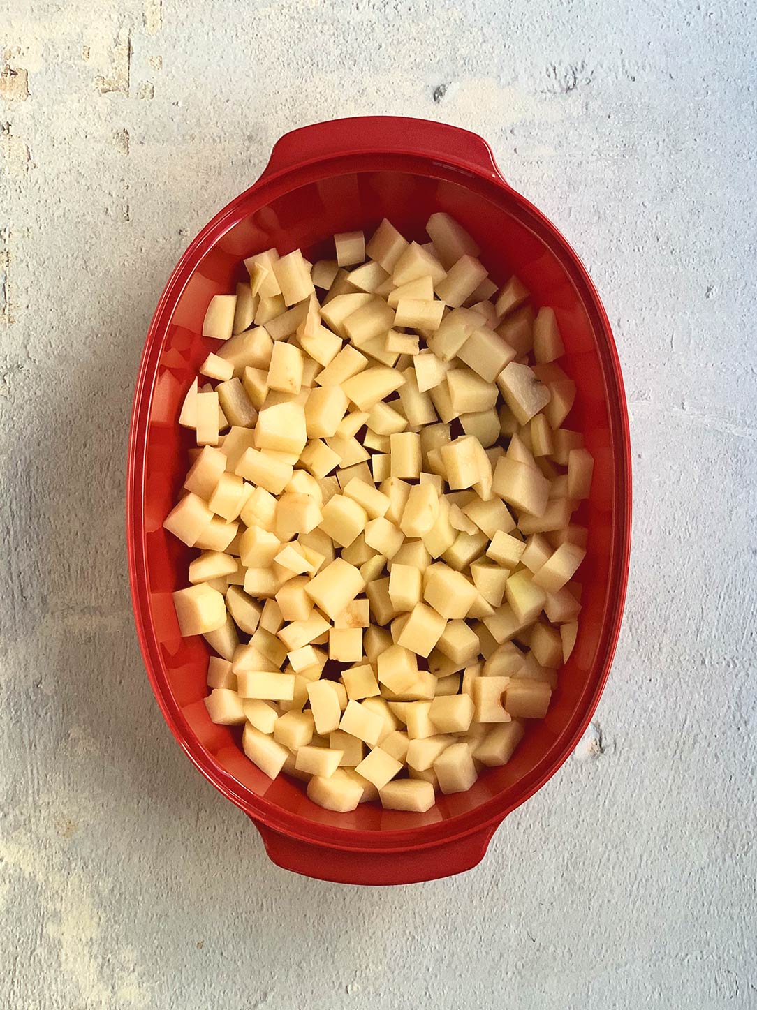 Diced potatoes in red microwave bowl.