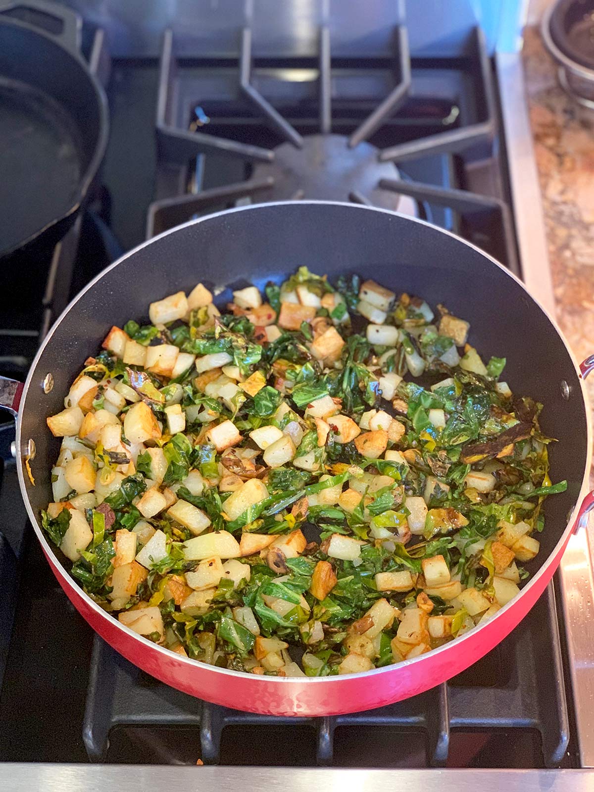 Greens and potatoes mixed together in the pan.