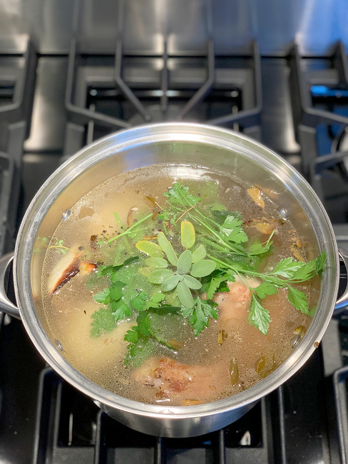 Water, roasted turkey and vegetables and fresh herbs in a large stock pot.