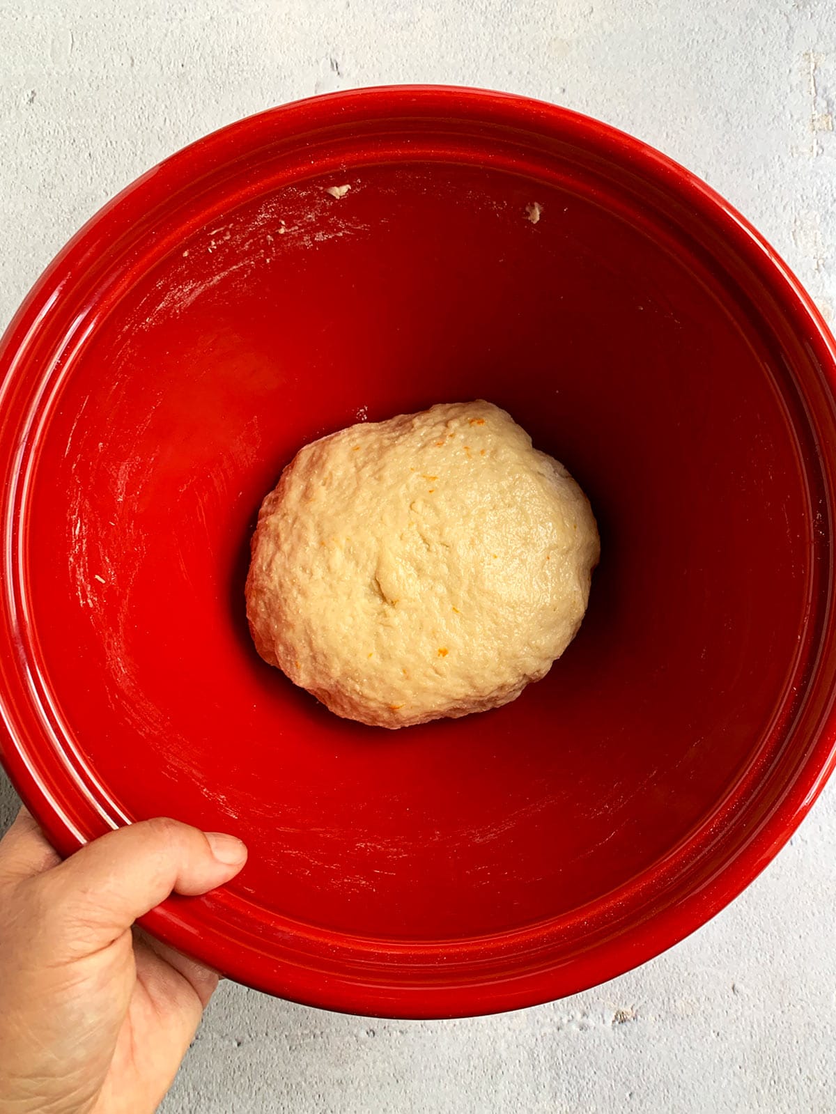 Donut dough ready to rise in a red bowl.