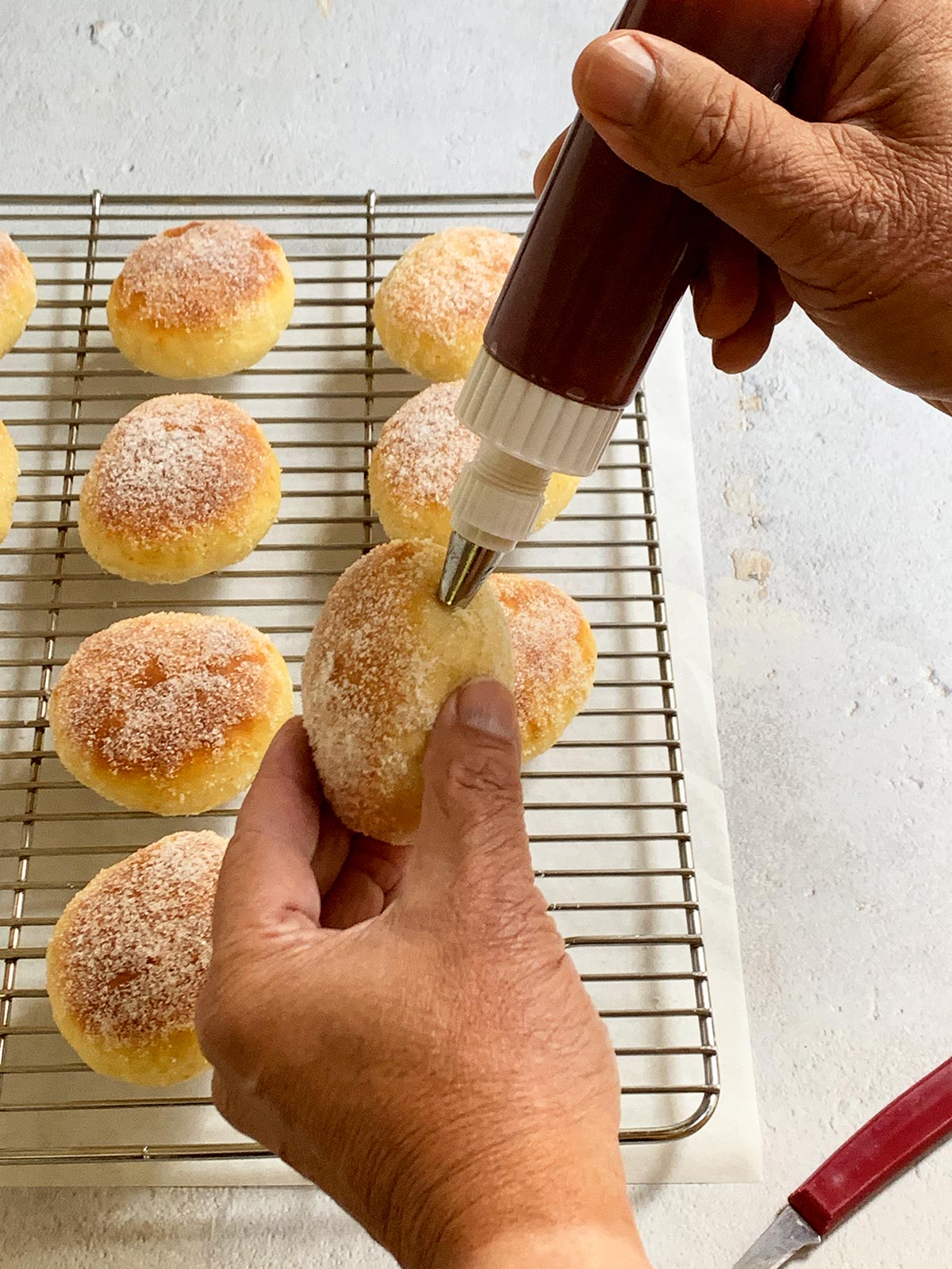 Squeezing jam into a baked sufganiyot.