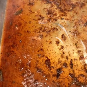 Close-up of roasting pan showing the liquid deglazing the pan.