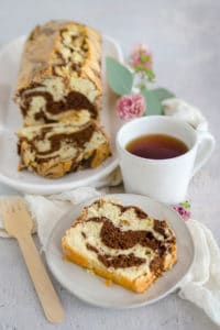 Slice of marble pound cake with a cup of coffee and more slices in the background.