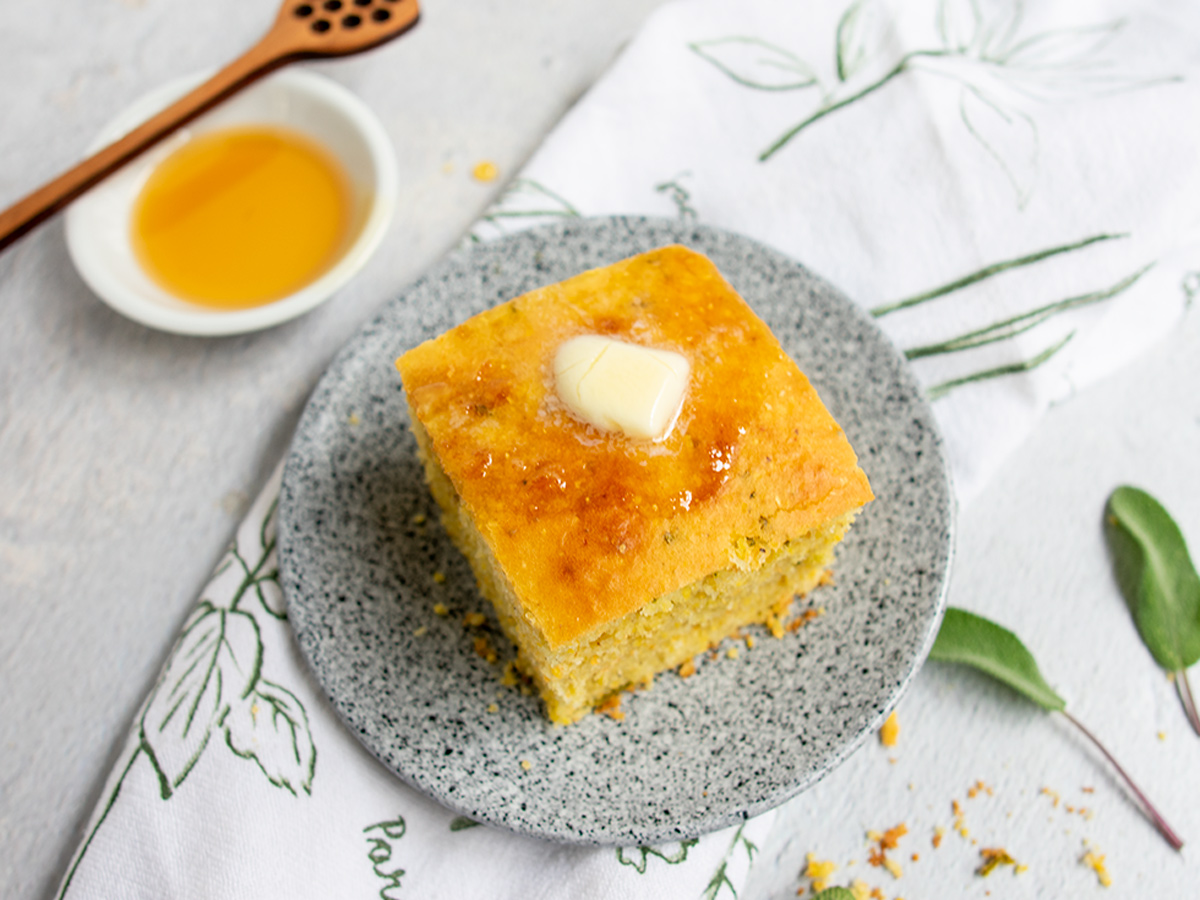 Square piece of cornbread with honey and melted butter on it.