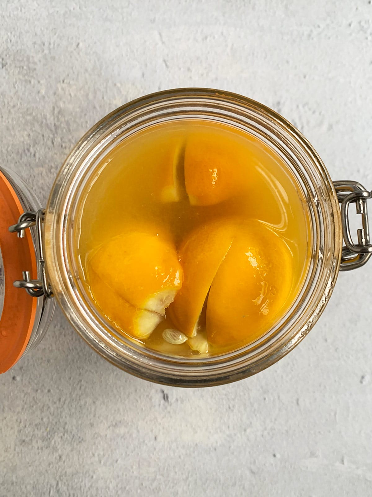 Top down view of Ottolenghi preserved lemons in a jar and completely covered in lemon juice.