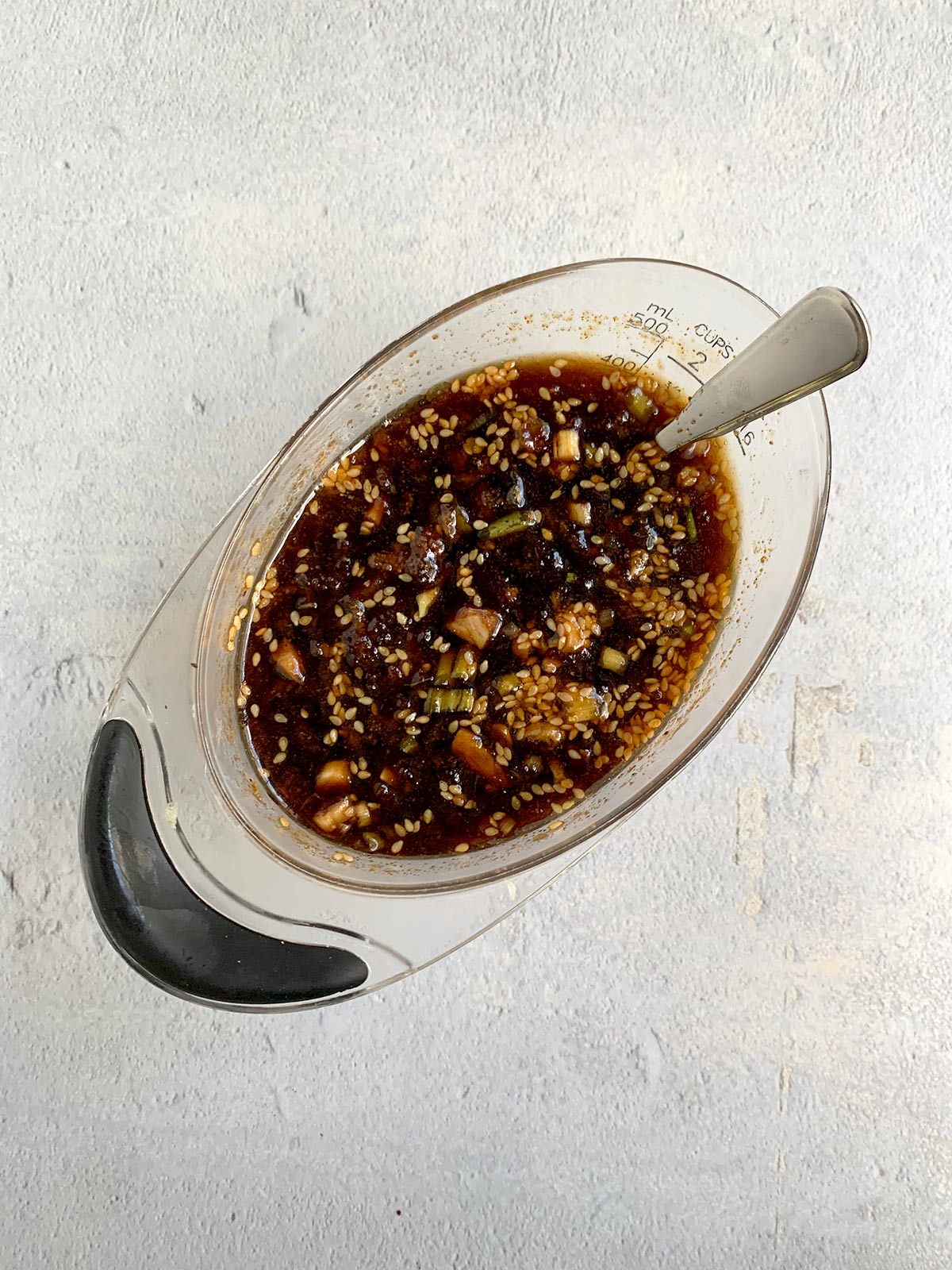 Kalbi marinade in a measuring cup on a light blue background.