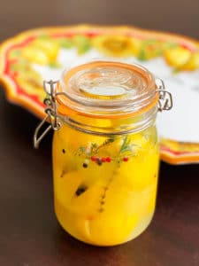 Jar of preserved lemons with a lemon plate in the background.