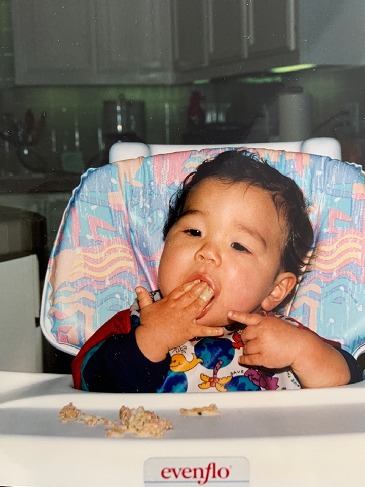 Gregory Lee eating mandu for the first time in a high chair.