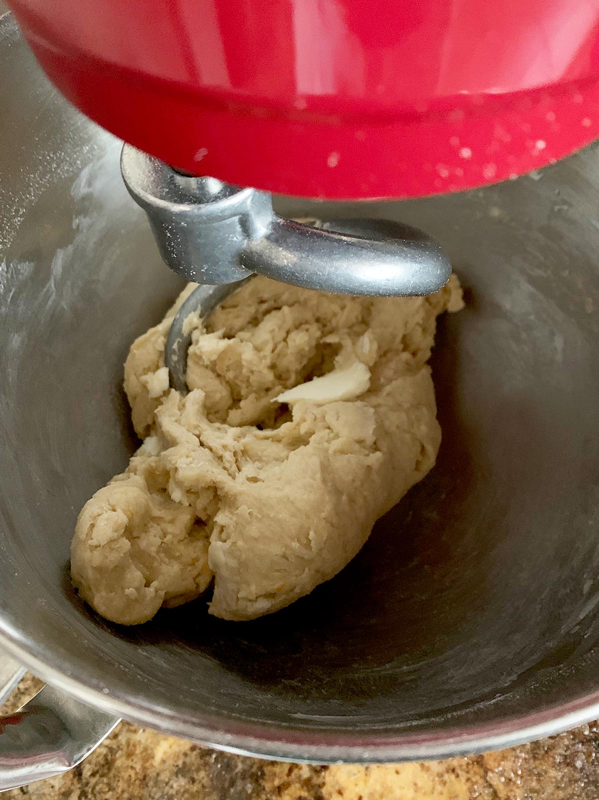 Babka dough in mixer and butter being added and incorporated.