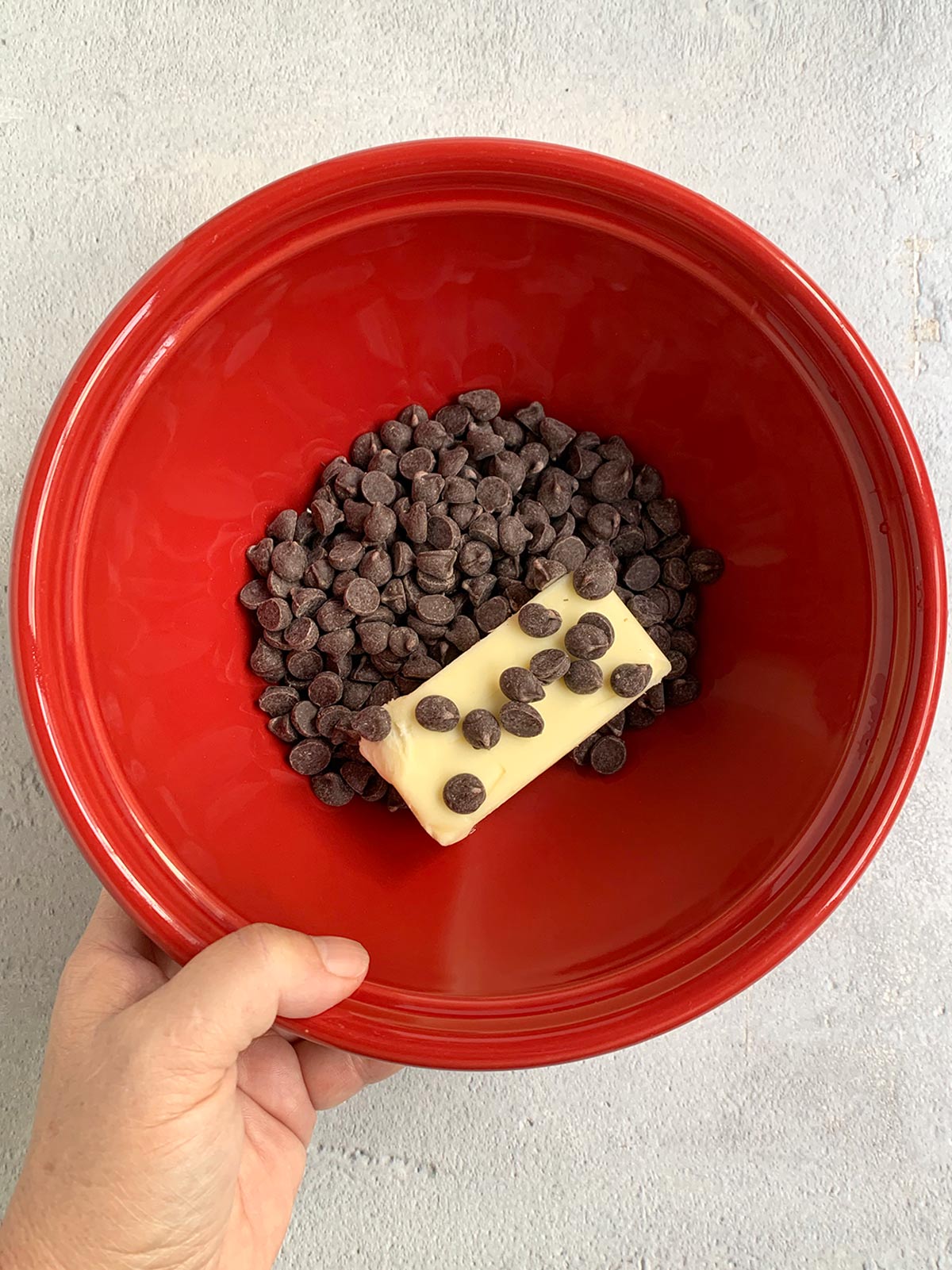 Chocolate chips and butter unmelted in a red bowl.