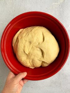 Babka dough in red bowl already risen.