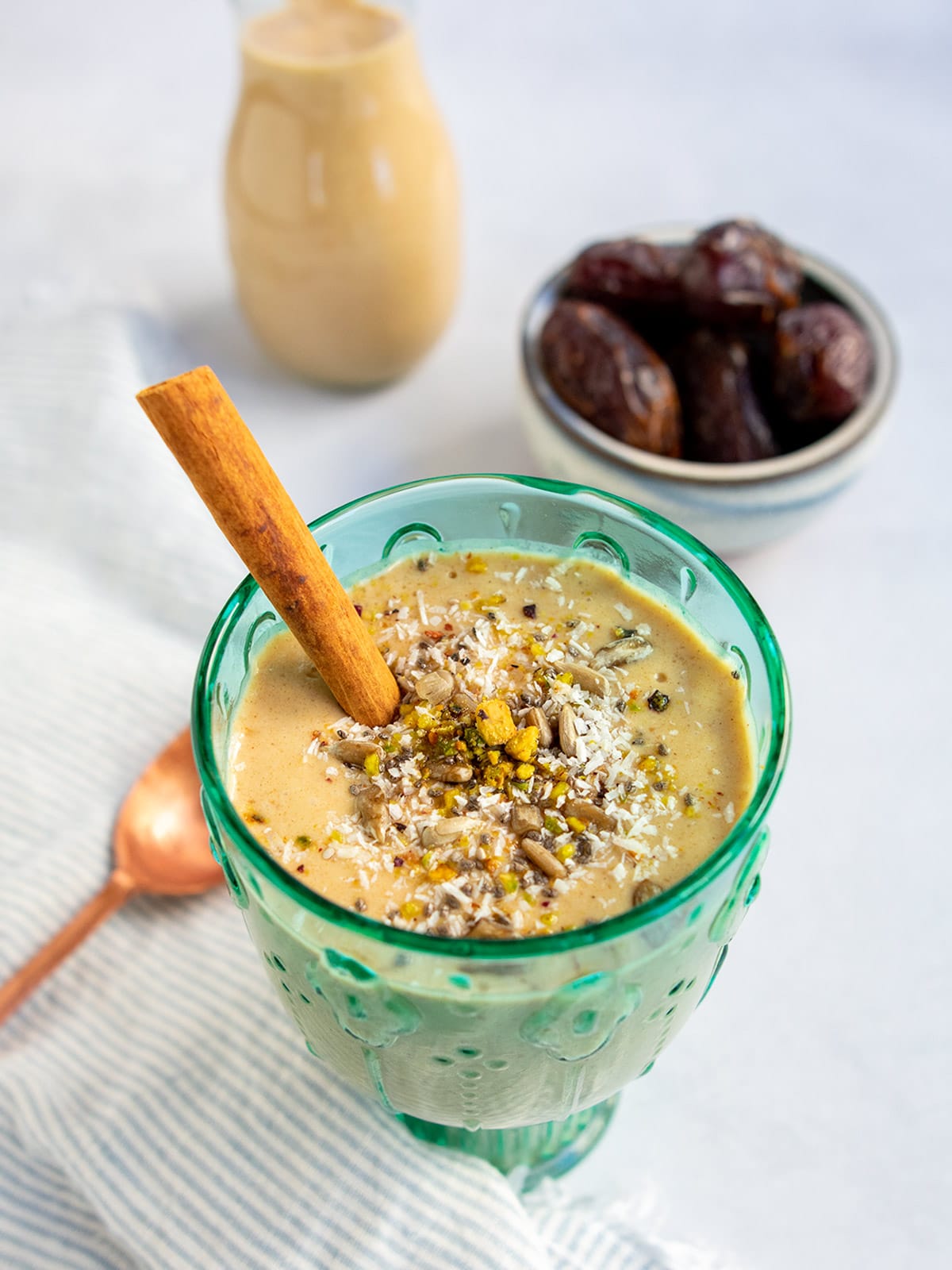 Date smoothie in a green glass with cinnamon stick.