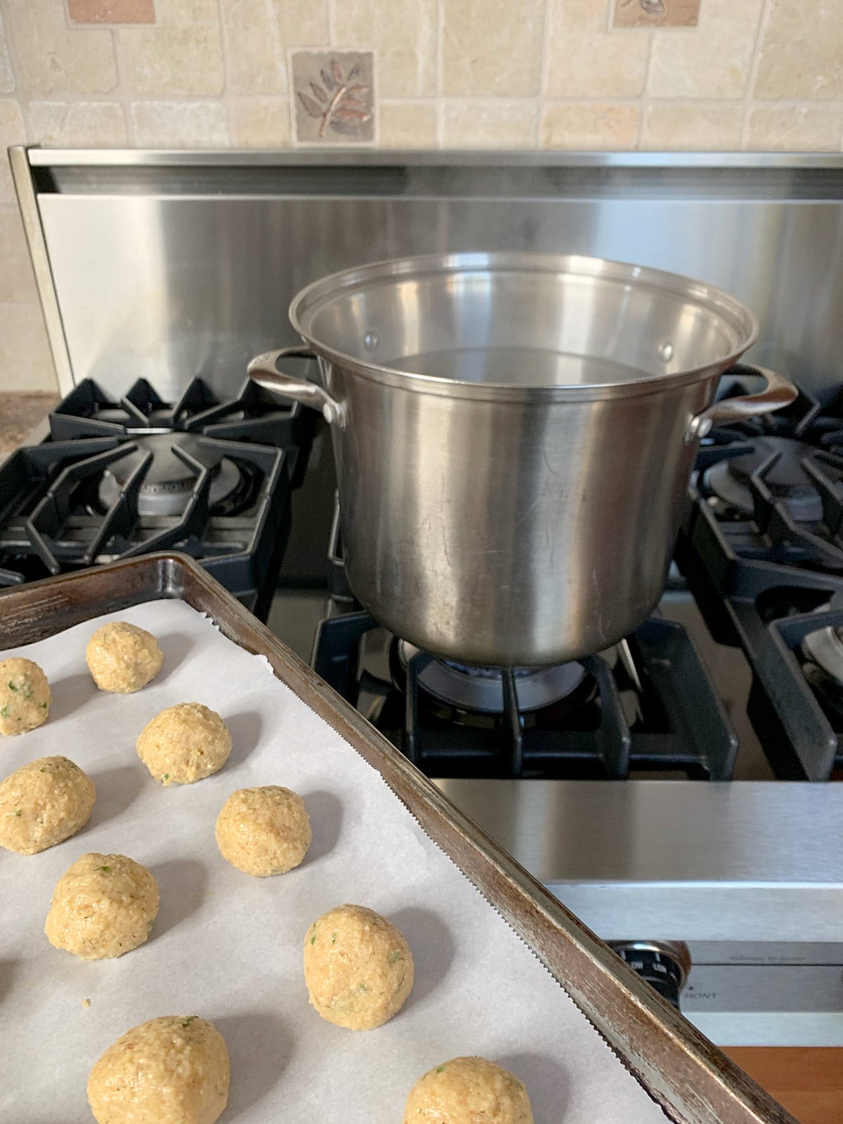 Uncooked matzo balls near a pot of boiling water.