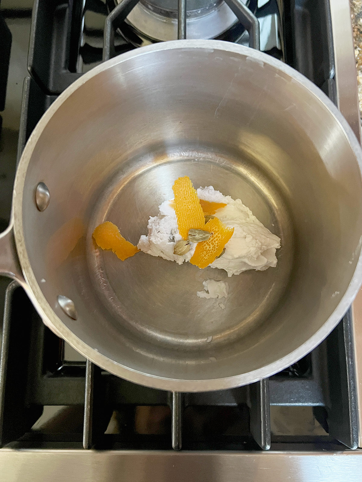 Coconut cream, cardamom and orange zest in a pot.