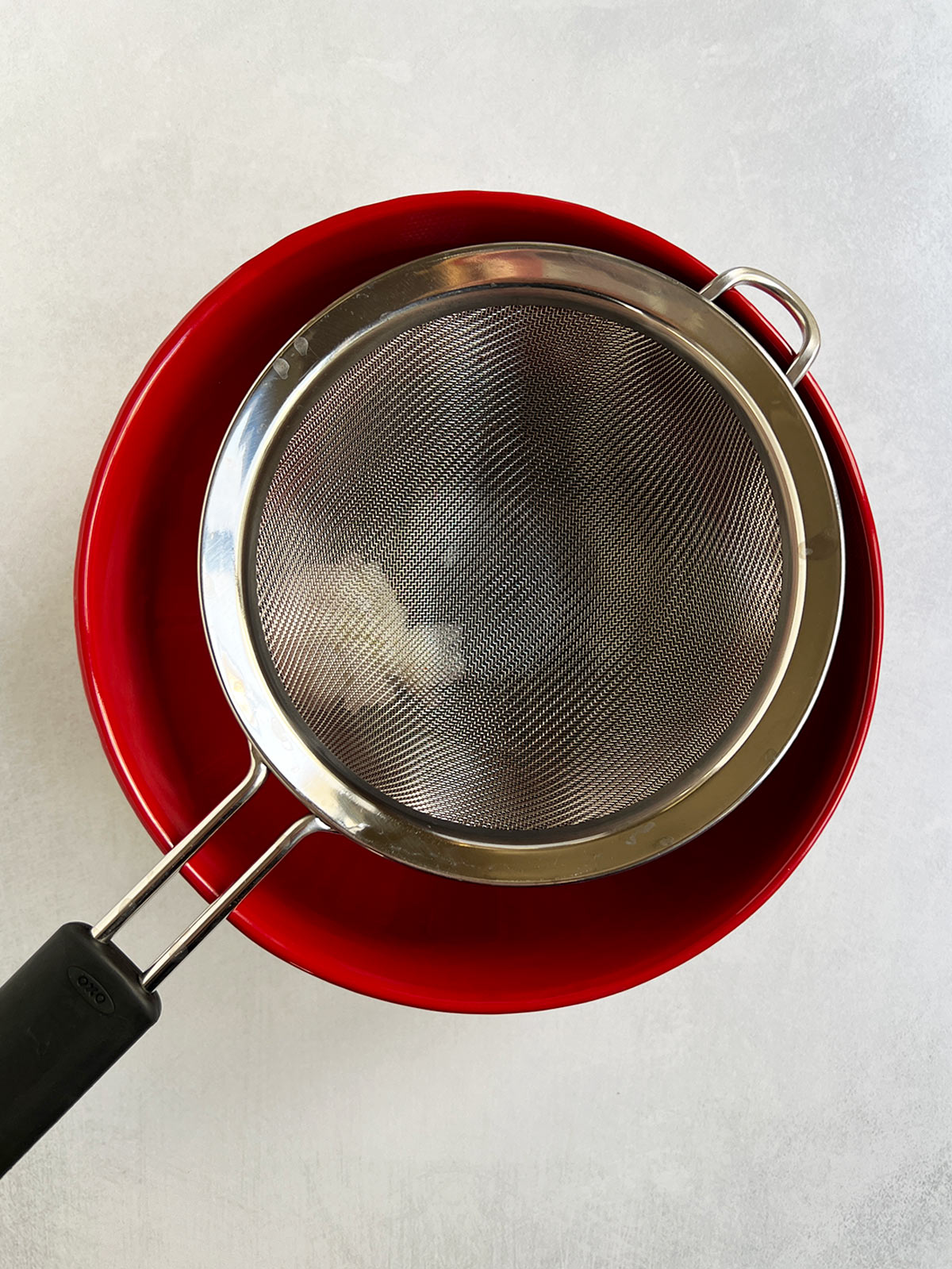 Strainer over a red bowl for chocolate truffle passover dessert.